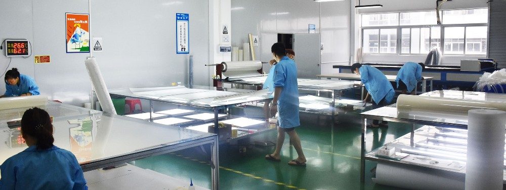 Workers inspecting smart film panels on light tables in a clean workshop